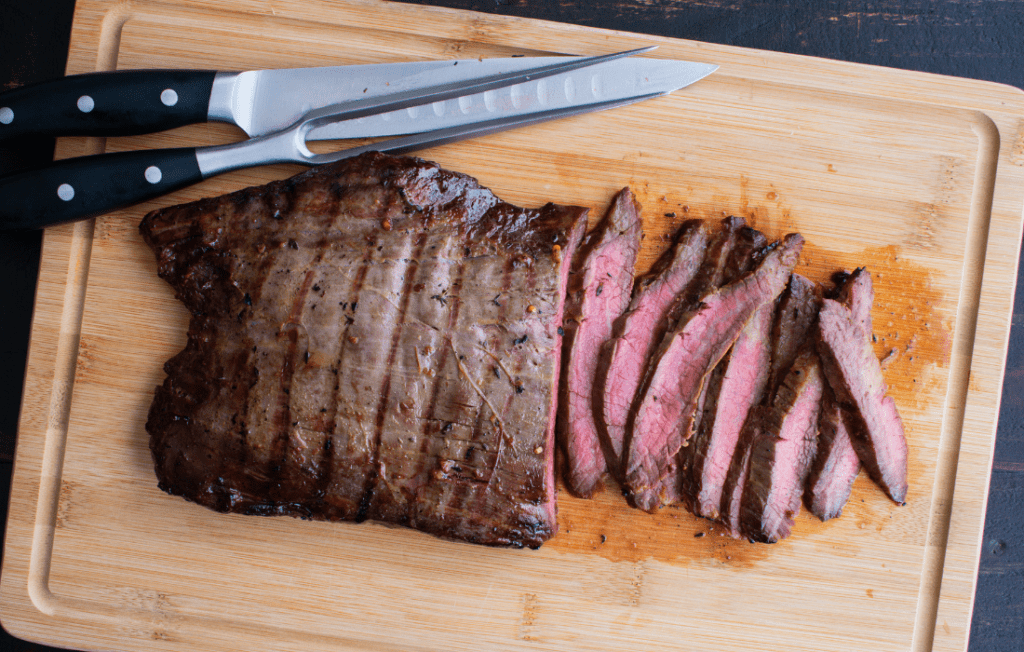 Cooked flank steak charred on the outside and a rosy pink/red on the inside
