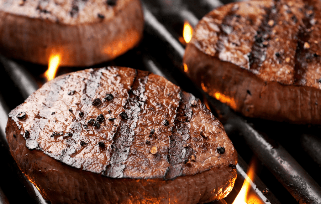 Filet mignon being seared over an open flame grill