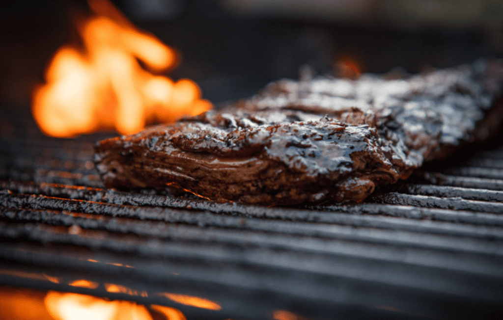 Flank Steak being seared over a flame on a grill