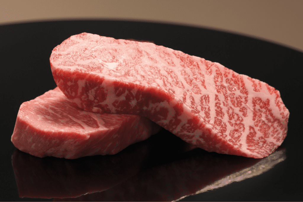 Close up of two pieces of cut wagyu stacked off one another to show glorious marbling