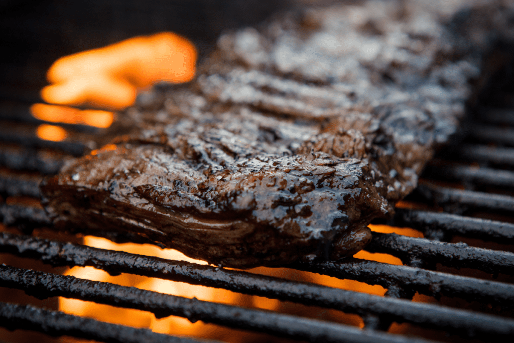 London broil being seared over a flame on a grill