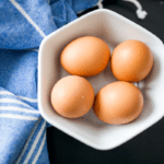 Four brown eggs in a bowl.