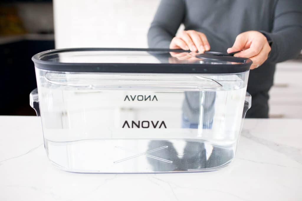 Anova sous vide container filled with water. Rack and lid fixed on the container.