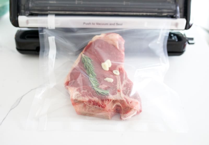 Foodsaver vacuum sealing a steak with rosemary and garlic