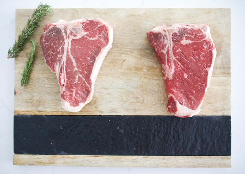 Porterhouse and T-bone steak side-by-side on a cutting board