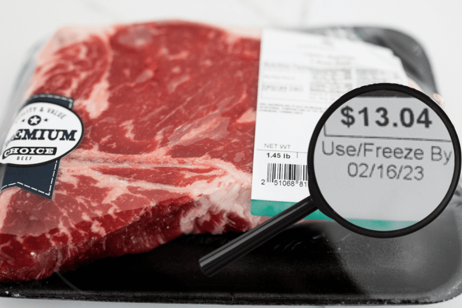 Steak in packaging with magnifying glass showing the expiration date.