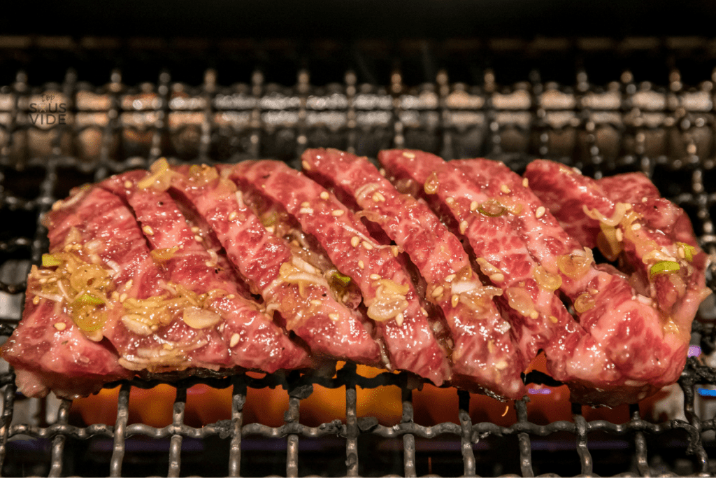 Wagyu being cooked on a grill, cut into small slices.