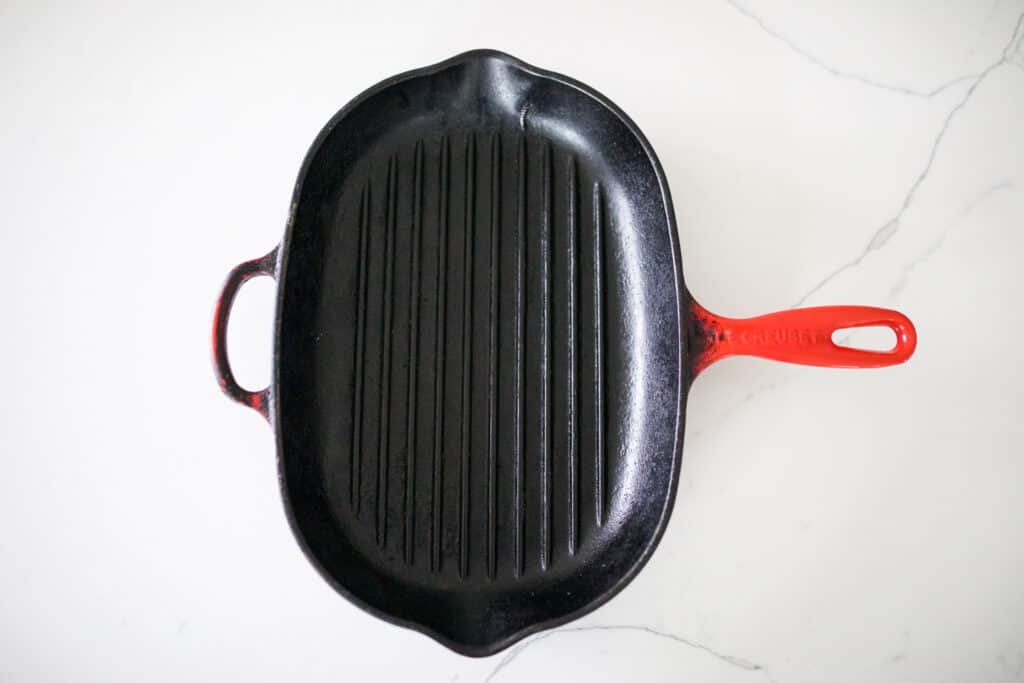 Cast iron pan with a red enamel handle.