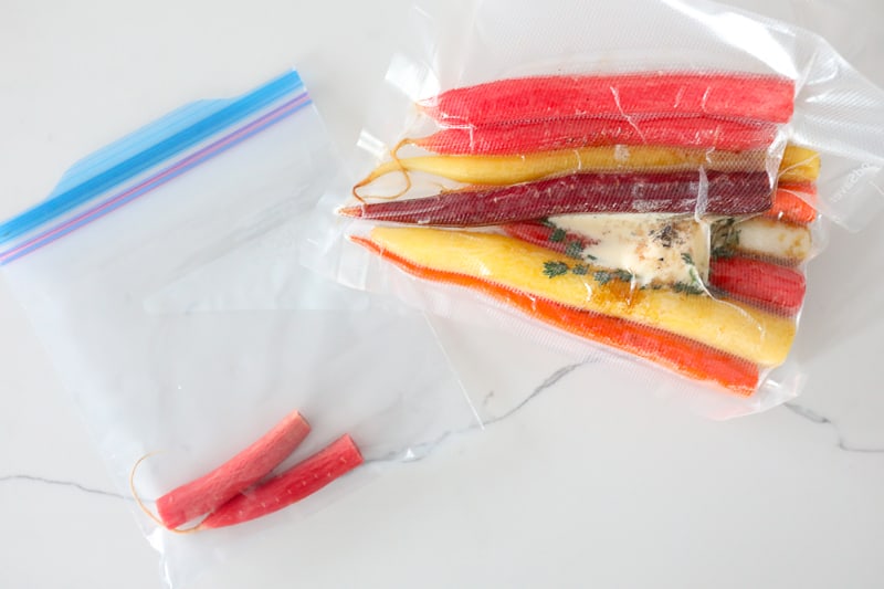 Two bags of carrots. One main bag vacuum sealed with many carrots and another Ziploc bag with two carrots.
