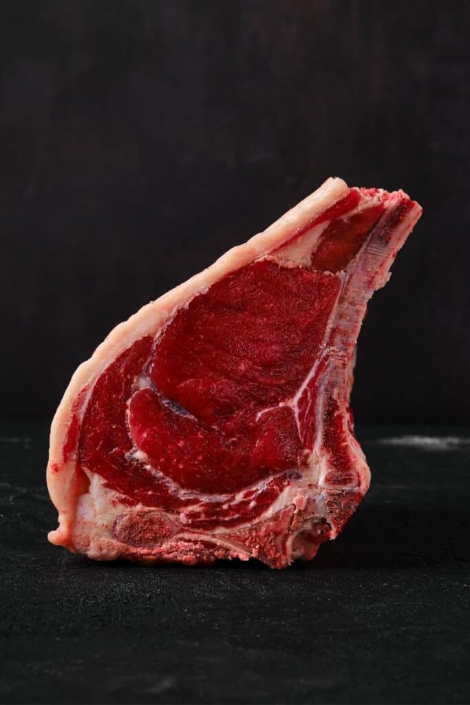 Bone in ribeye standing up with all black background.