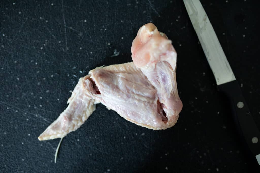 Chicken wing with incisions at ridges to parse into three pieces.