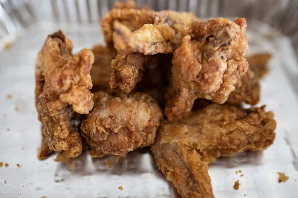 Fried chicken wings in a foil pan.