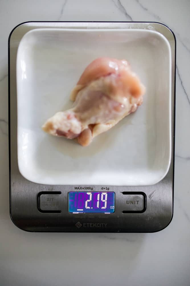 Chicken drum being weighed on a scale. Scale reads 2 pounds and 2 ounces.