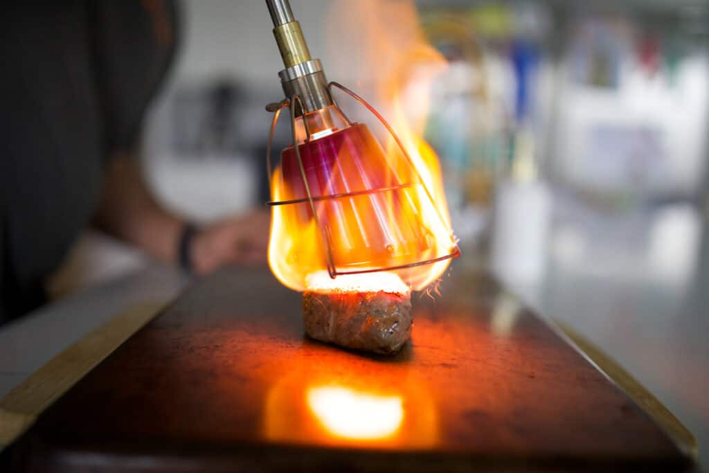 New York strip being seared with a Searzall. You can see heavy dispersed flame from the Searzall.