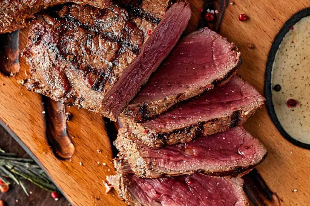 Close up of a blue rare steak sliced on a cutting board.