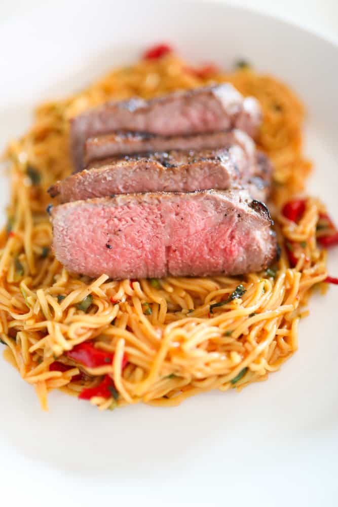 New York Strip sliced on a bed of longevity noodles.
