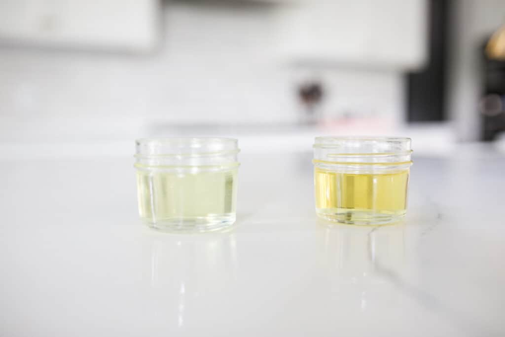 Corn oil and vegetable oil in small jars next to each other for color comparison.