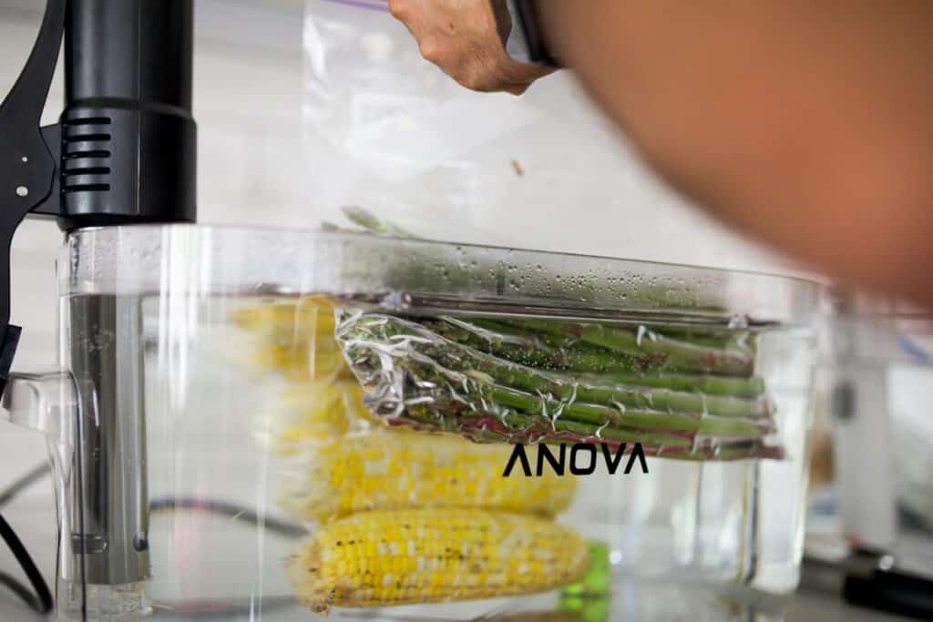 Asparagus and corn being cooked in a sous vide bath.