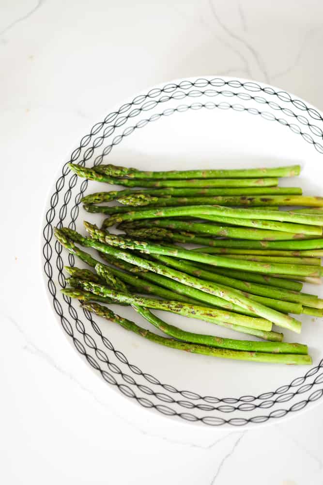 Bright green cooked asparagus with a bit of char on a plate.
