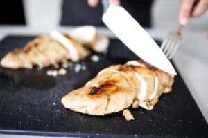 Chicken breast being sliced on a cutting board.