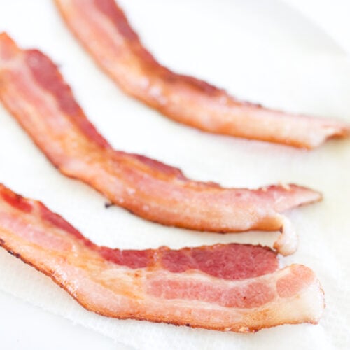 Three strips of bacon on paper towel lined plate.