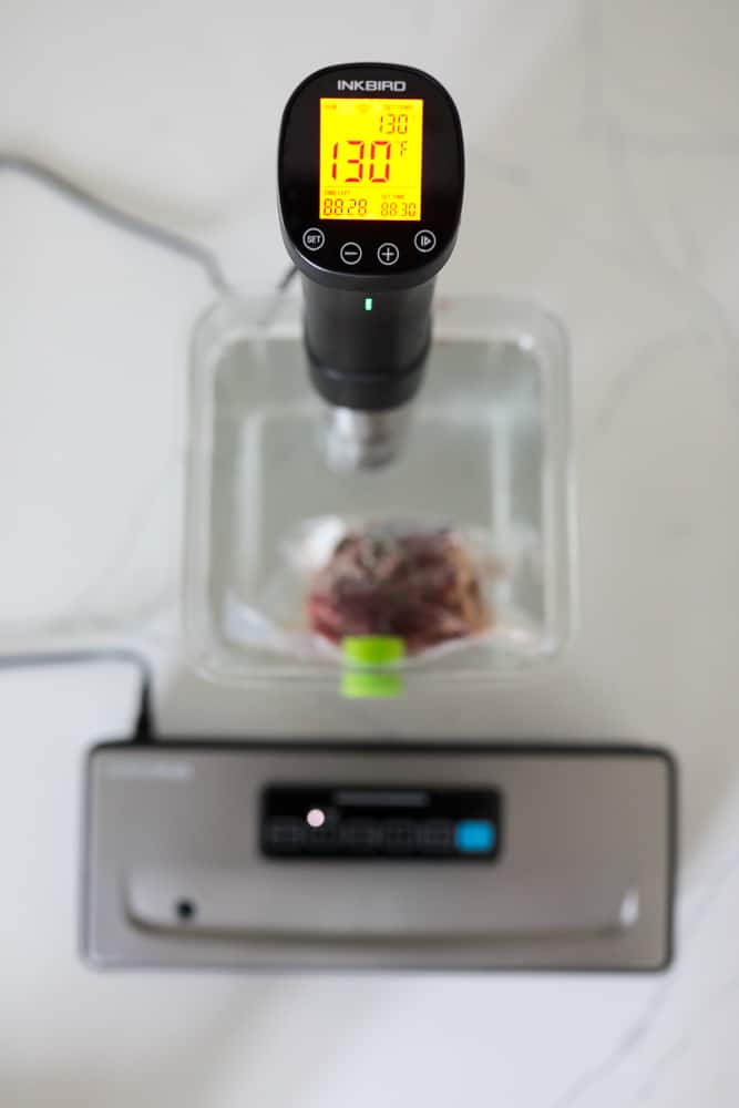 INKBIRD sous vide machine cooking steak. Display on cooker shown prominently.